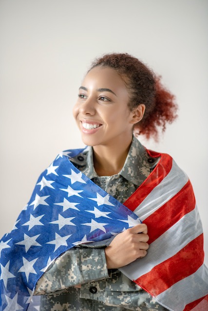 Military person sitting with American flag draped over shoulders finding relief and starting to relax